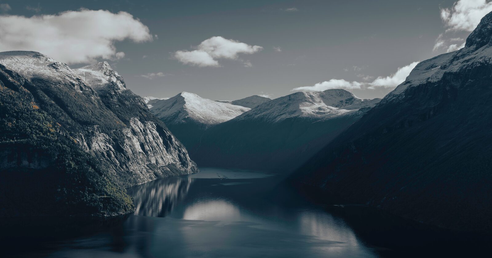 A calm Norwegian fjord flanked by snow-capped mountains